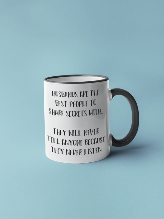 White mug with black handle, featuring the funny quote 'husbands are the best people to share secrets with. They will never tell anyone because they never listen'. Printed in black ink.