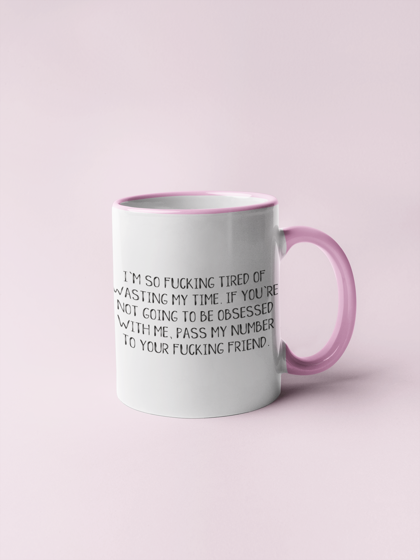 White ceramic mug with a pink rim & handle. Featuring the funny quote 'i'm so fucking tired of wasting my time. If you're not going to be obsessed with me, pass my number to your friend'. Printed in black ink.