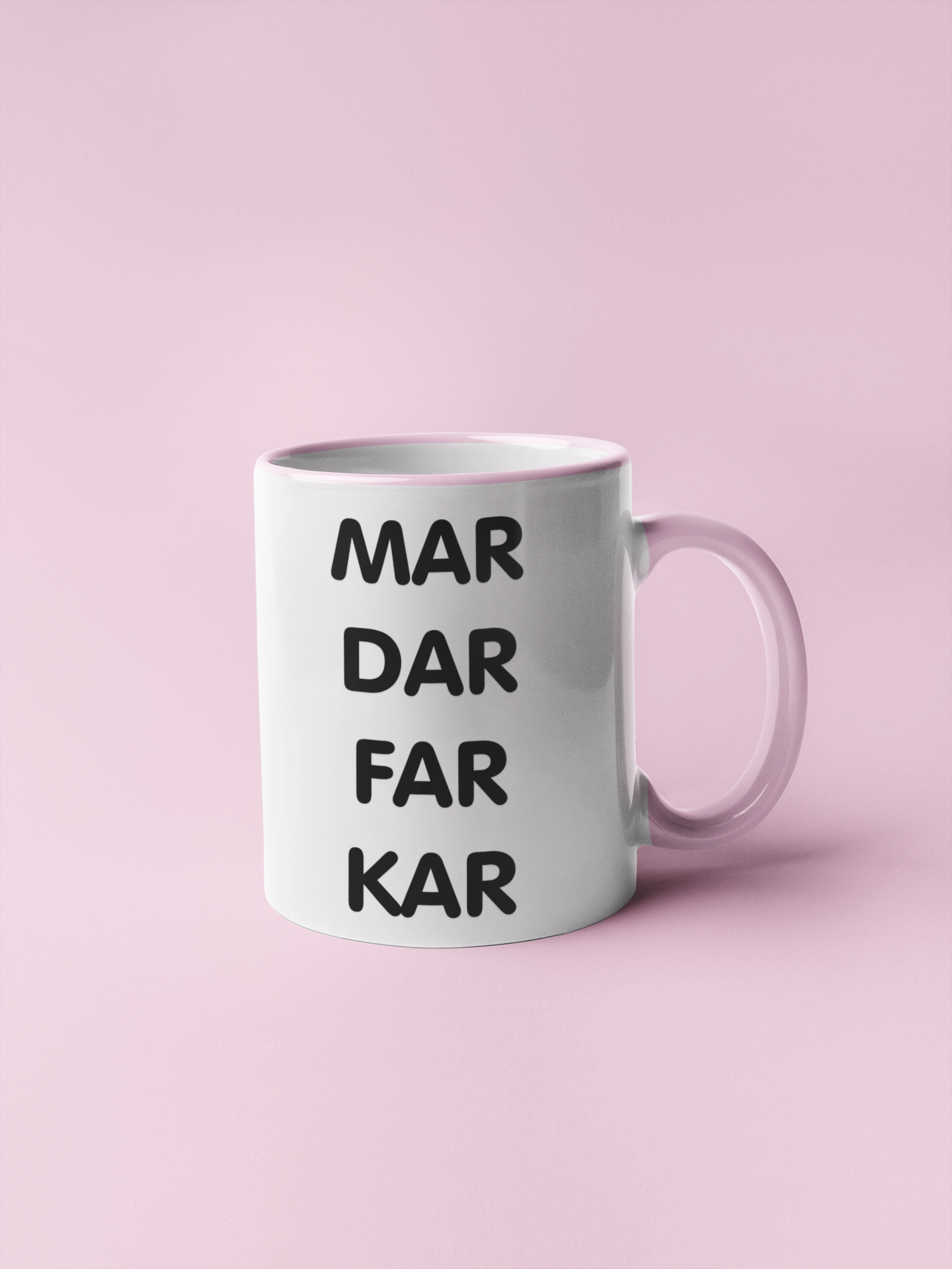 White mug with a pink handle and rim, featuring a bold quote to the middle which reads mar dar far kar. Printed in black ink.