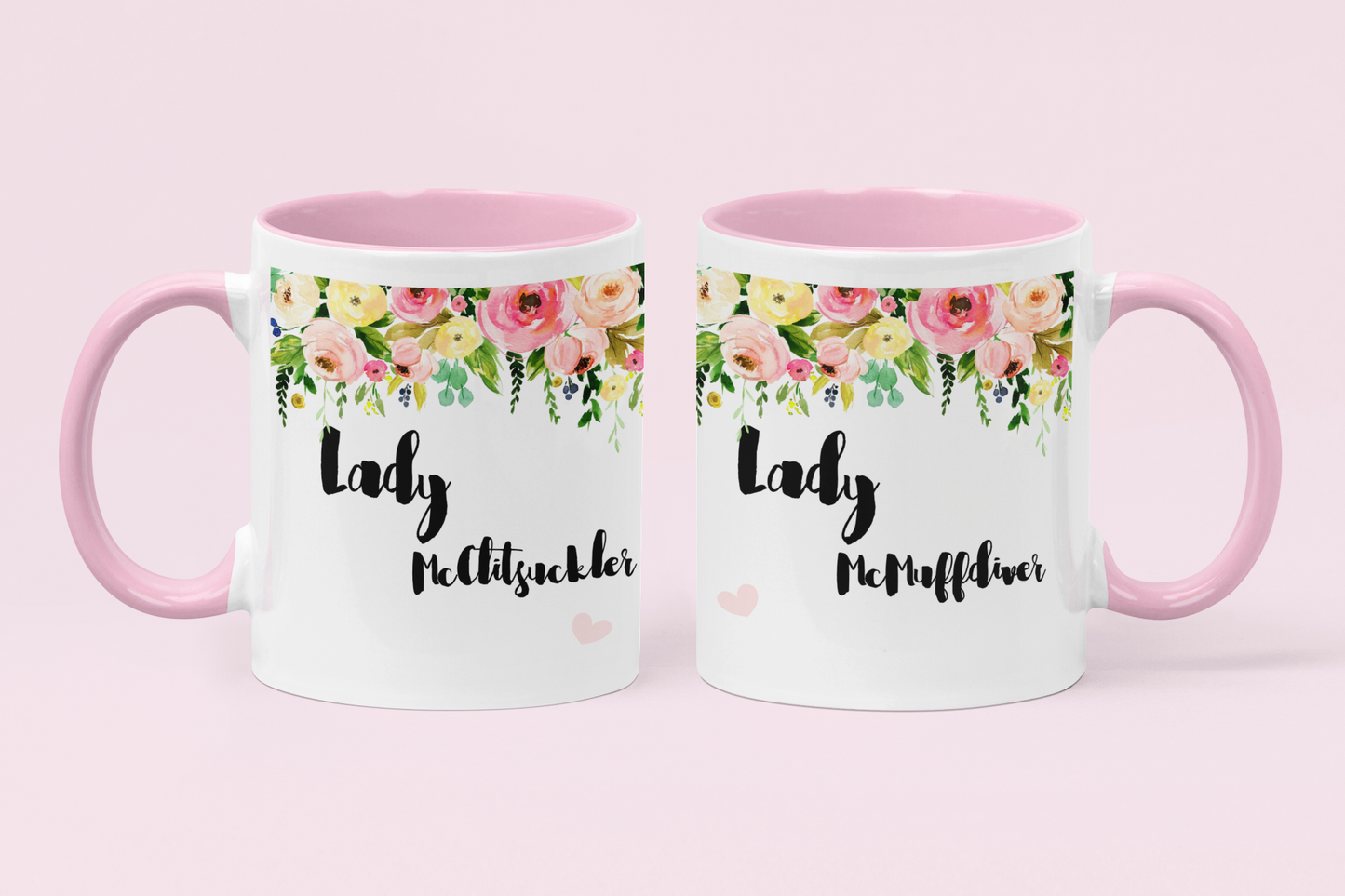 A pair of white mugs with pink handles & a colourful floral banner to the top. Under is the funny quotes ' lady mcclitsuckler' and 'lady mcmuffdiver'.