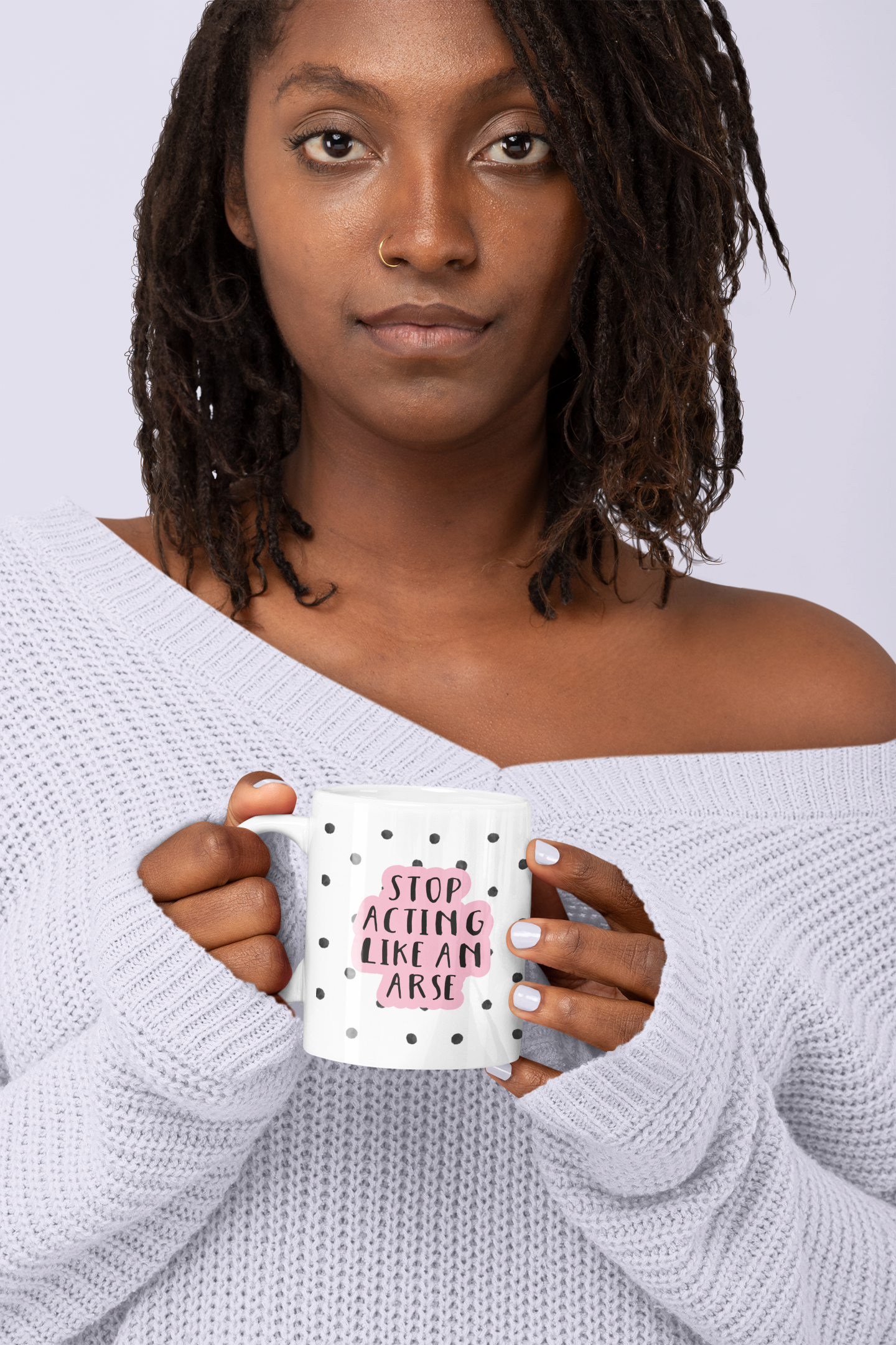 White ceramic mug with a black water-coloured spotty background & the quote 'stop acting like an arse' situated over the top. The wording is printed in black with a baby pink outline.