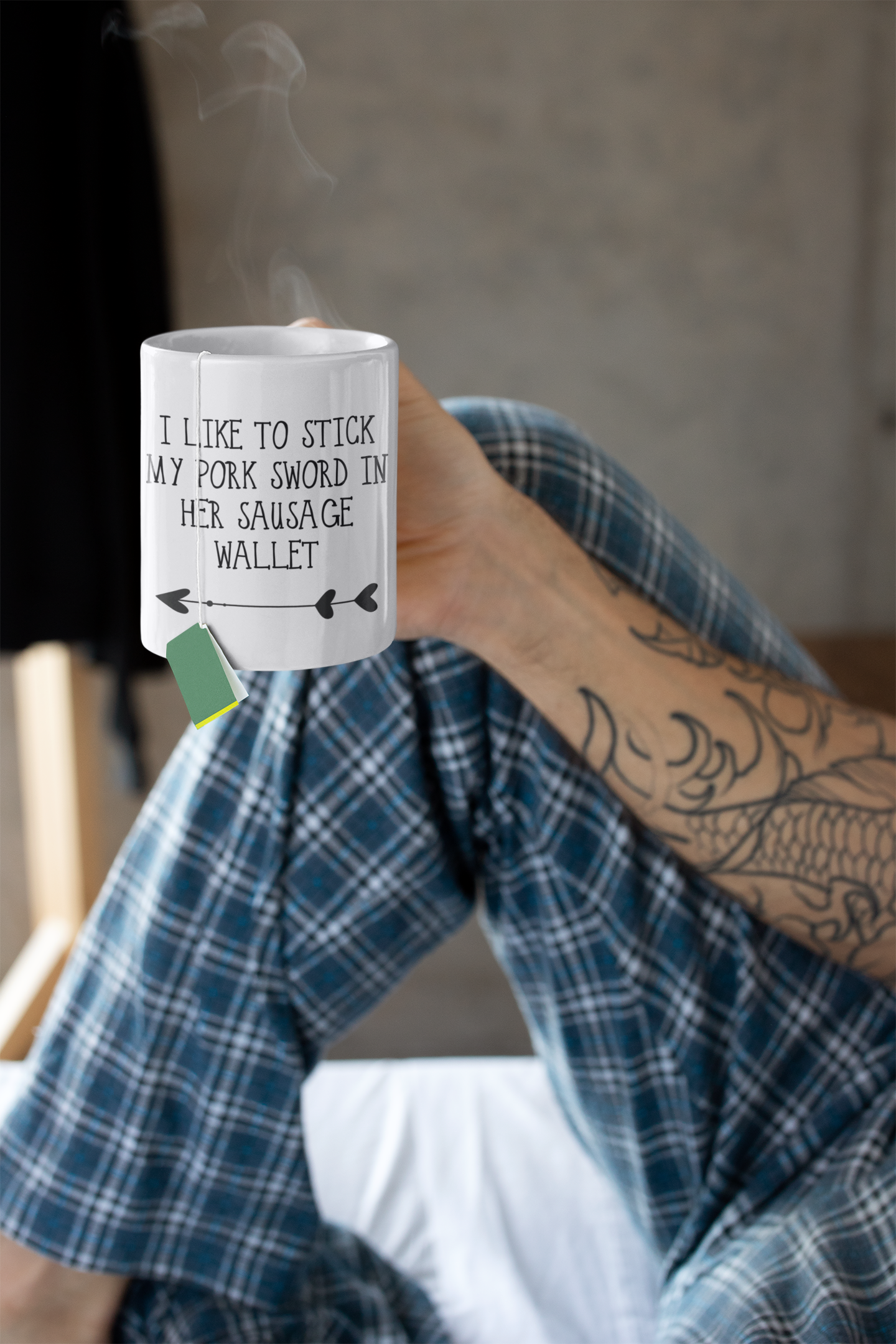 Man holding a white mug with a funny quote reading 'i like to stick my pork sword in her sausage wallet' with an arrow underneath, pointing to the left. Printed in black ink.