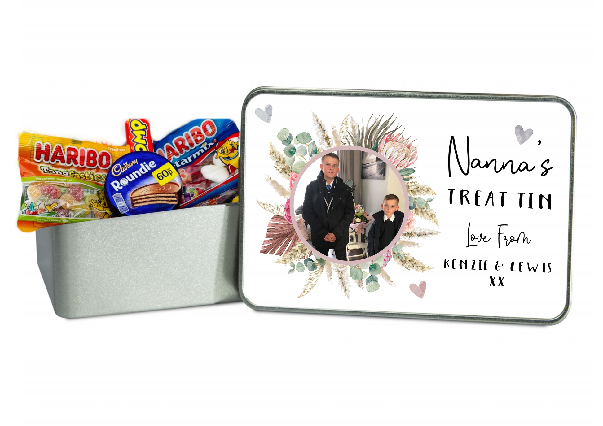 Square metal treat tin with a white slip lid. To the front of the lid it has a colourful floral design wreath with a personalised photo of 2 children in the middle. To the right of the flower is the words 'nanna's treat tin, love...'. Printed in black ink.