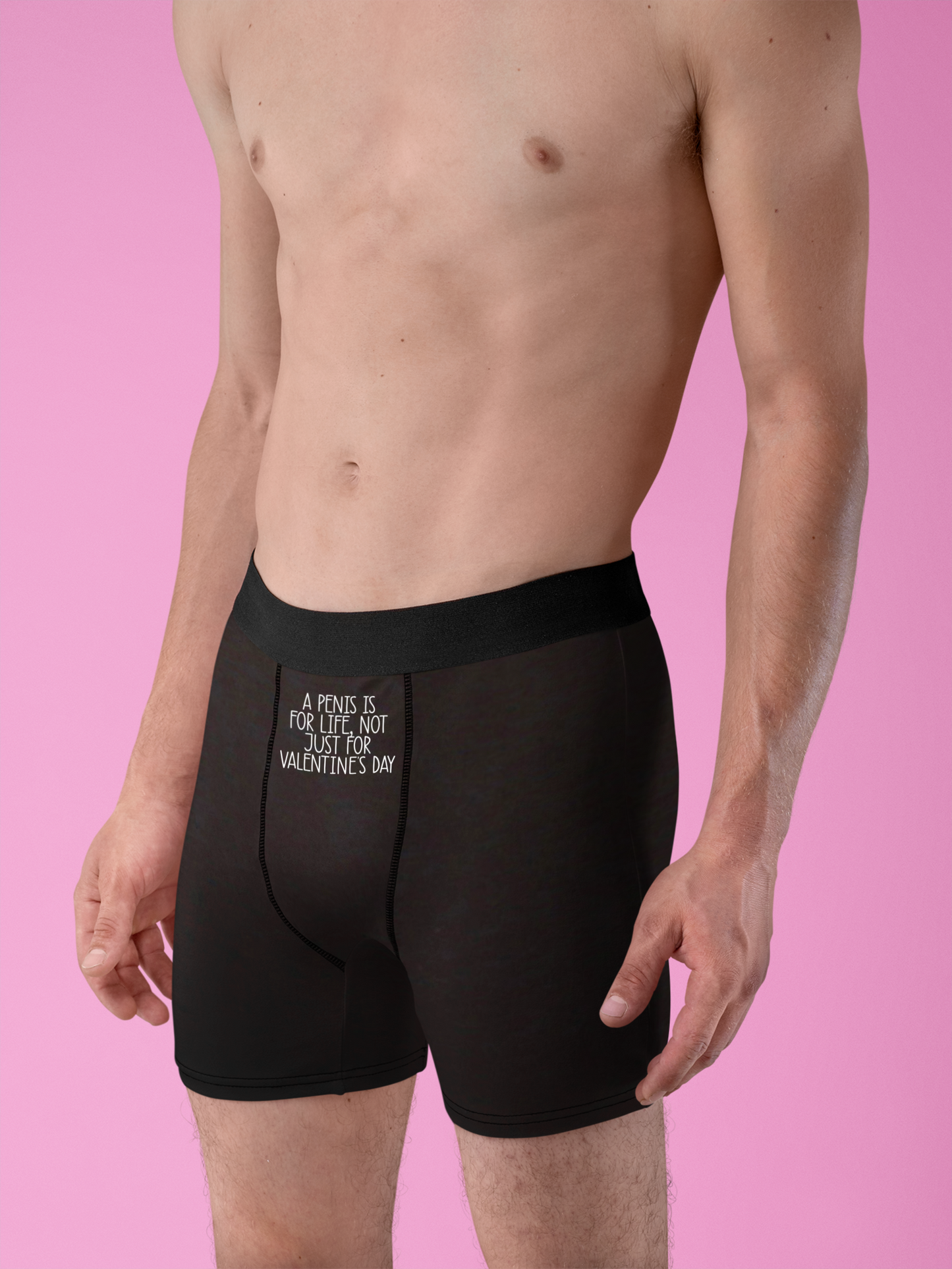 Black pair of mens boxer short pants with a white funny quote to the top middle section.. It reads 'a penis is for life, not just for valentine's day'.