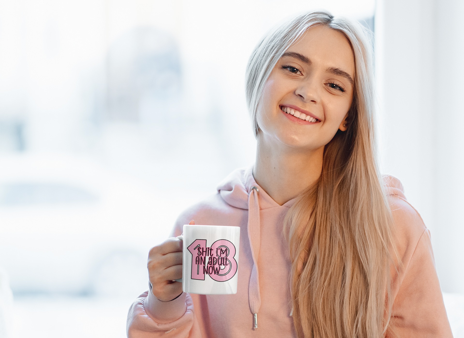 White mug with a bold 18 in baby pink and over the top it reads shit i'm an adult now