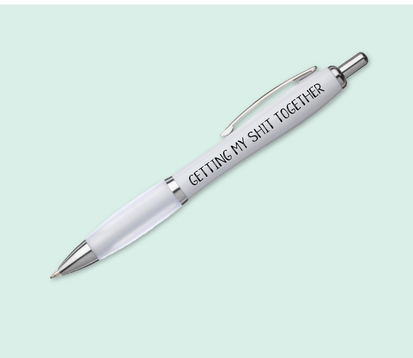 A white pen with silver accents & a white, soft grip barrel. The funny quote 'getting my shit together' is printed to the spine in black ink.