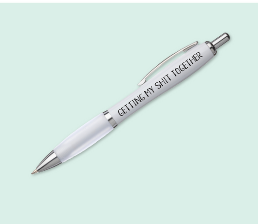 A white pen with silver accents & a white, soft grip barrel. The funny quote 'getting my shit together' is printed to the spine in black ink.