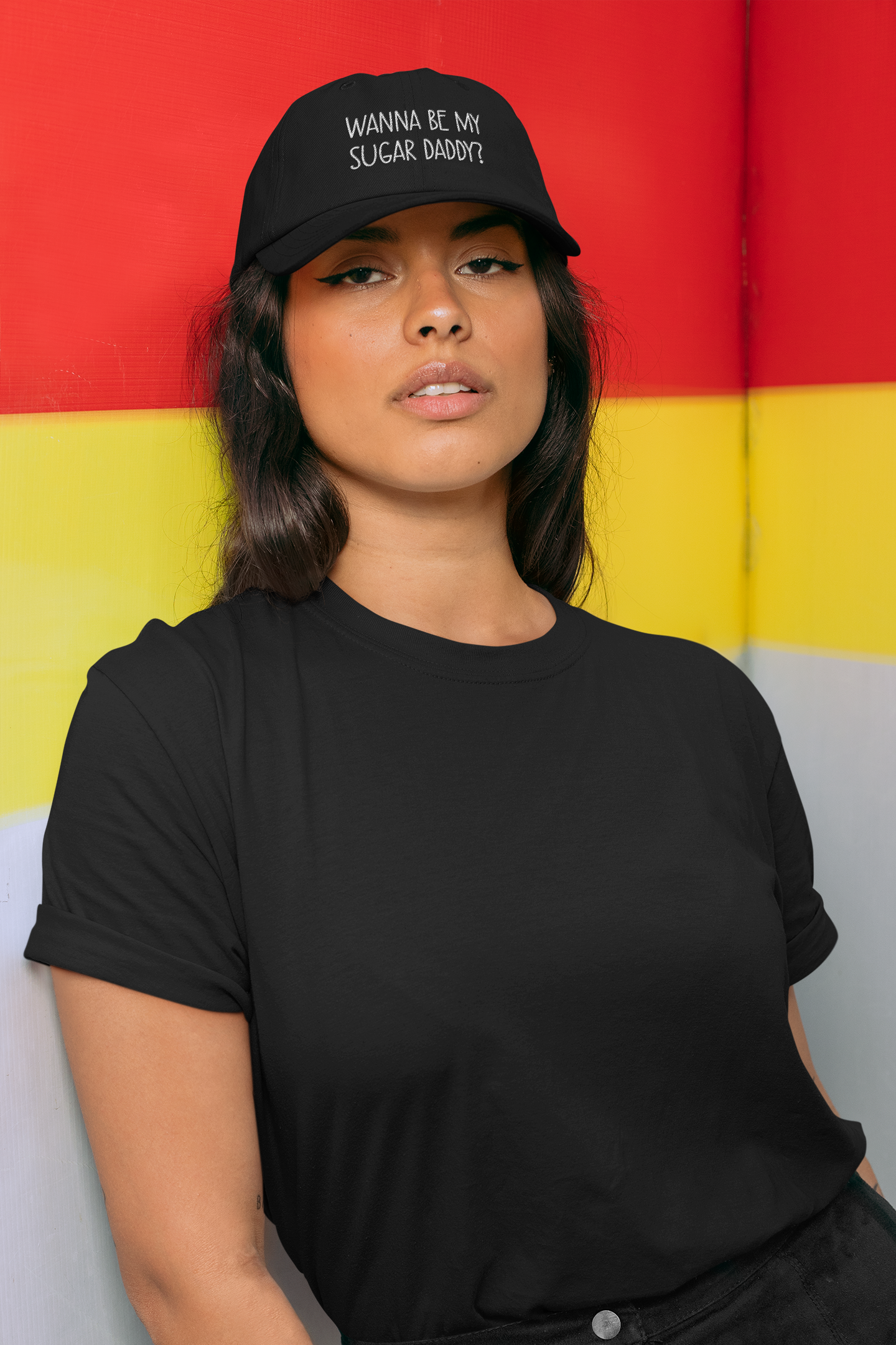 A lady wearing a black cotton cap with white lettering to the front which reads 'wanna be my sugar daddy?'.