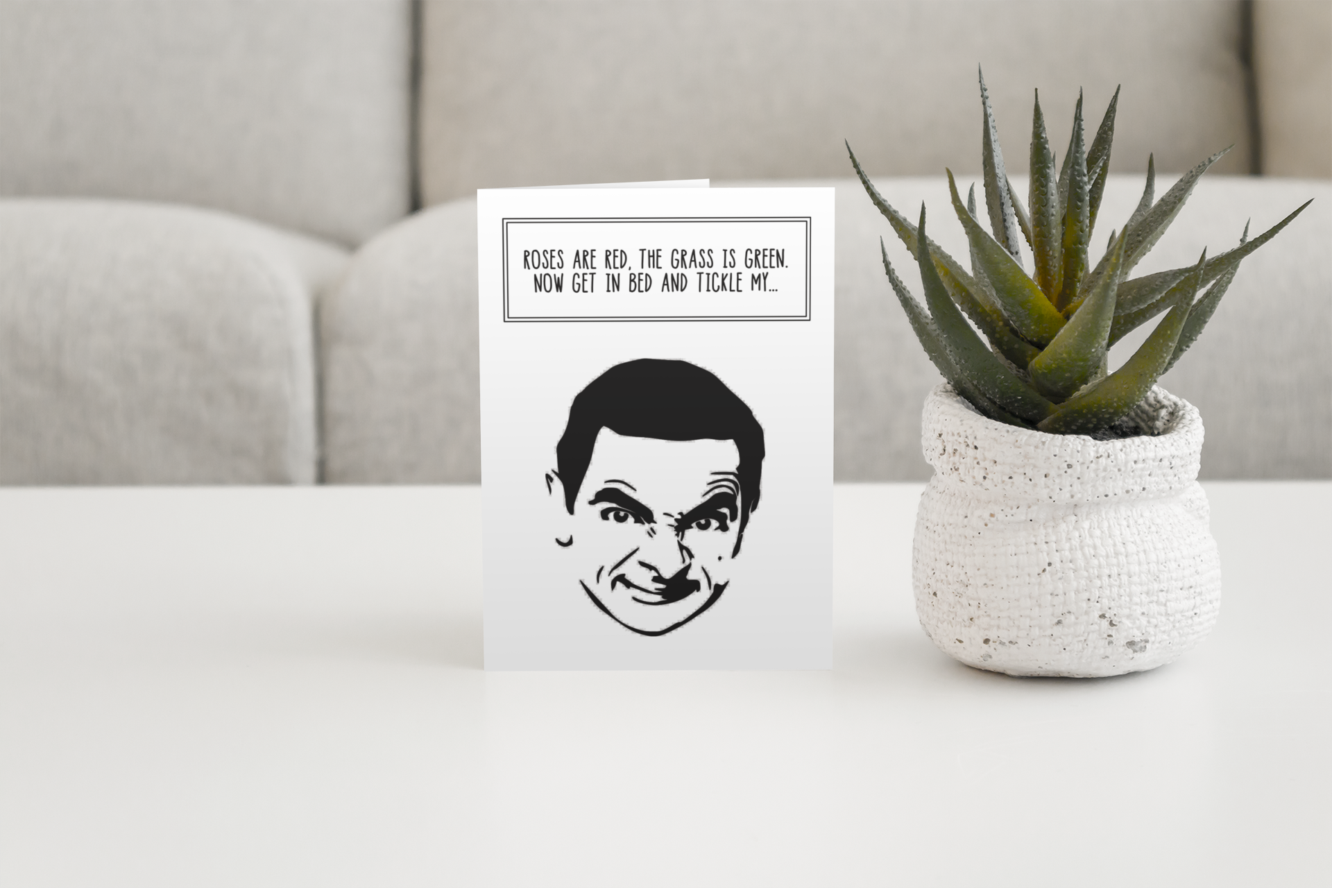 A white vertical greetings card featuring a silhouette of Mr Bean. To the top it reads 'roses are red, the grass is green, get in bed & tickle my...'. Printed in black ink.