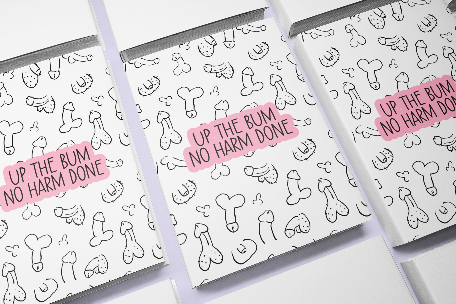 A white A5 notebook featuring a fun willy design print to the front. Over the print is a funny quote 'up the bum, no harm done', printed in black & pink ink. The notebook is folded & stapled, containing 40 plain pages.
