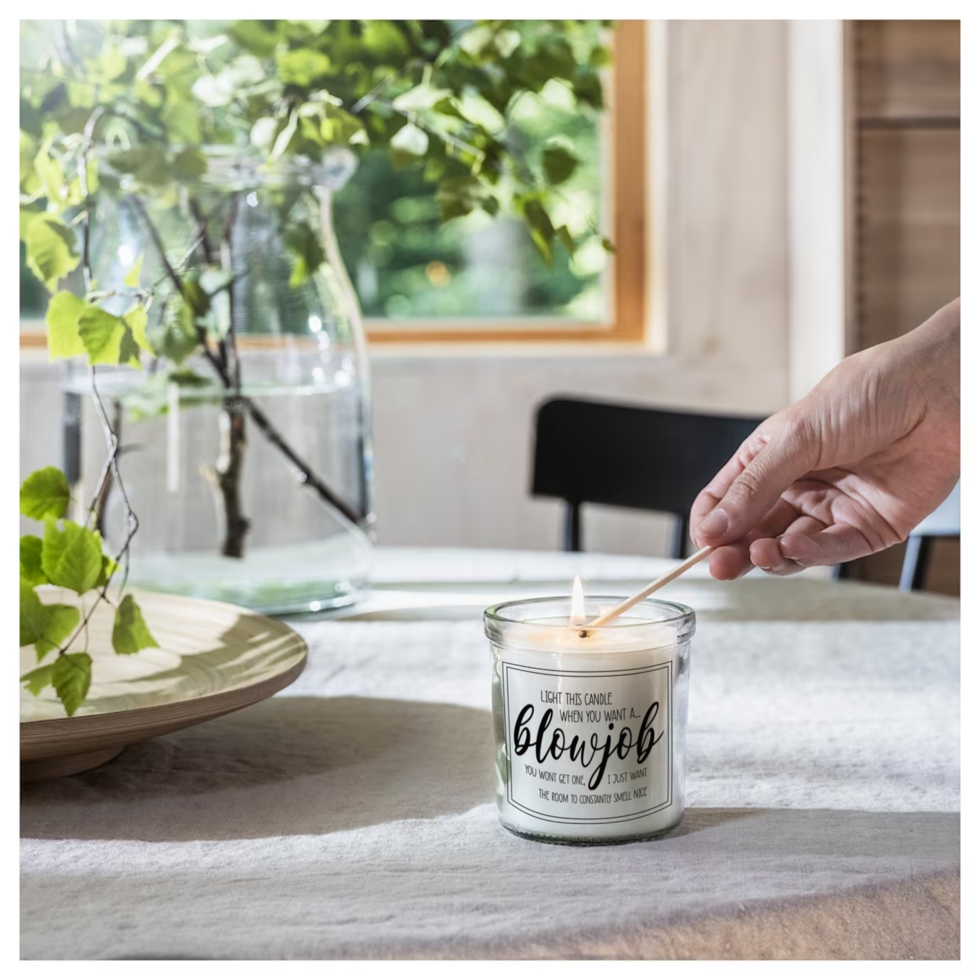 Glass jar candle with white wax. Clear label to the front features a funny quote which reads 'light this candle when you want a blowjob. You won't get one, i just want the room to constantly smell nice'. 