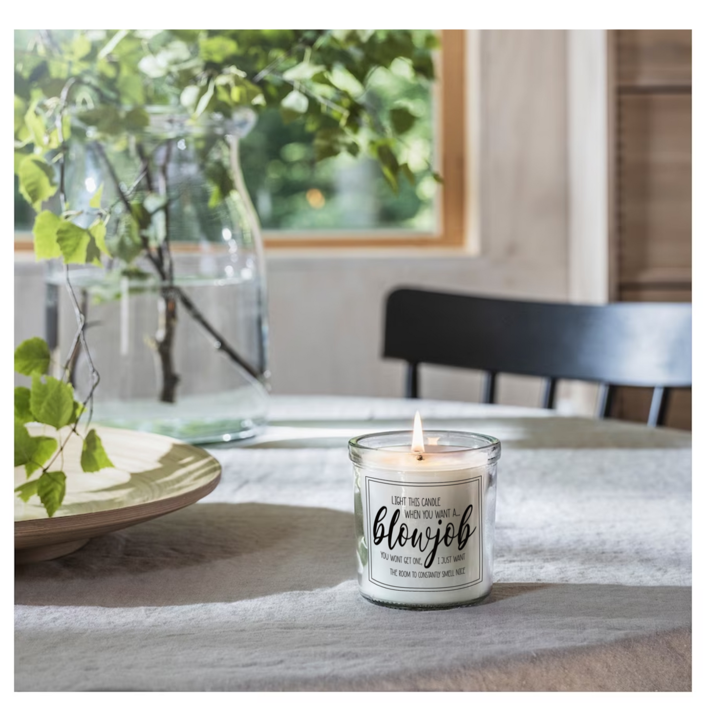 Glass jar candle with white wax. Clear label to the front features a funny quote which reads 'light this candle when you want a blowjob. You won't get one, i just want the room to constantly smell nice'. 